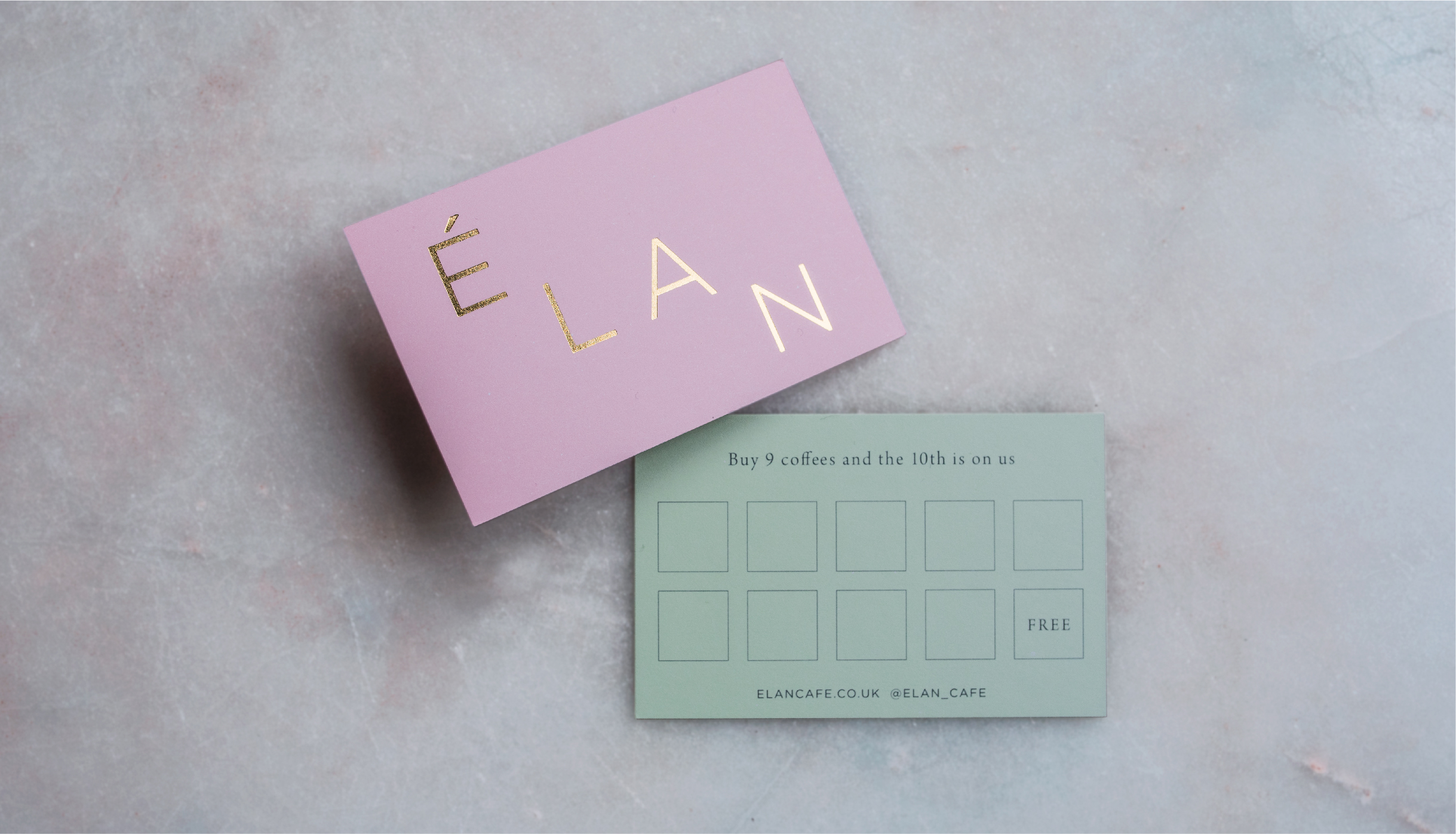 Graphic design of Elan Café loyalty card. Gold foil logo on pink and green card shot on marble background
